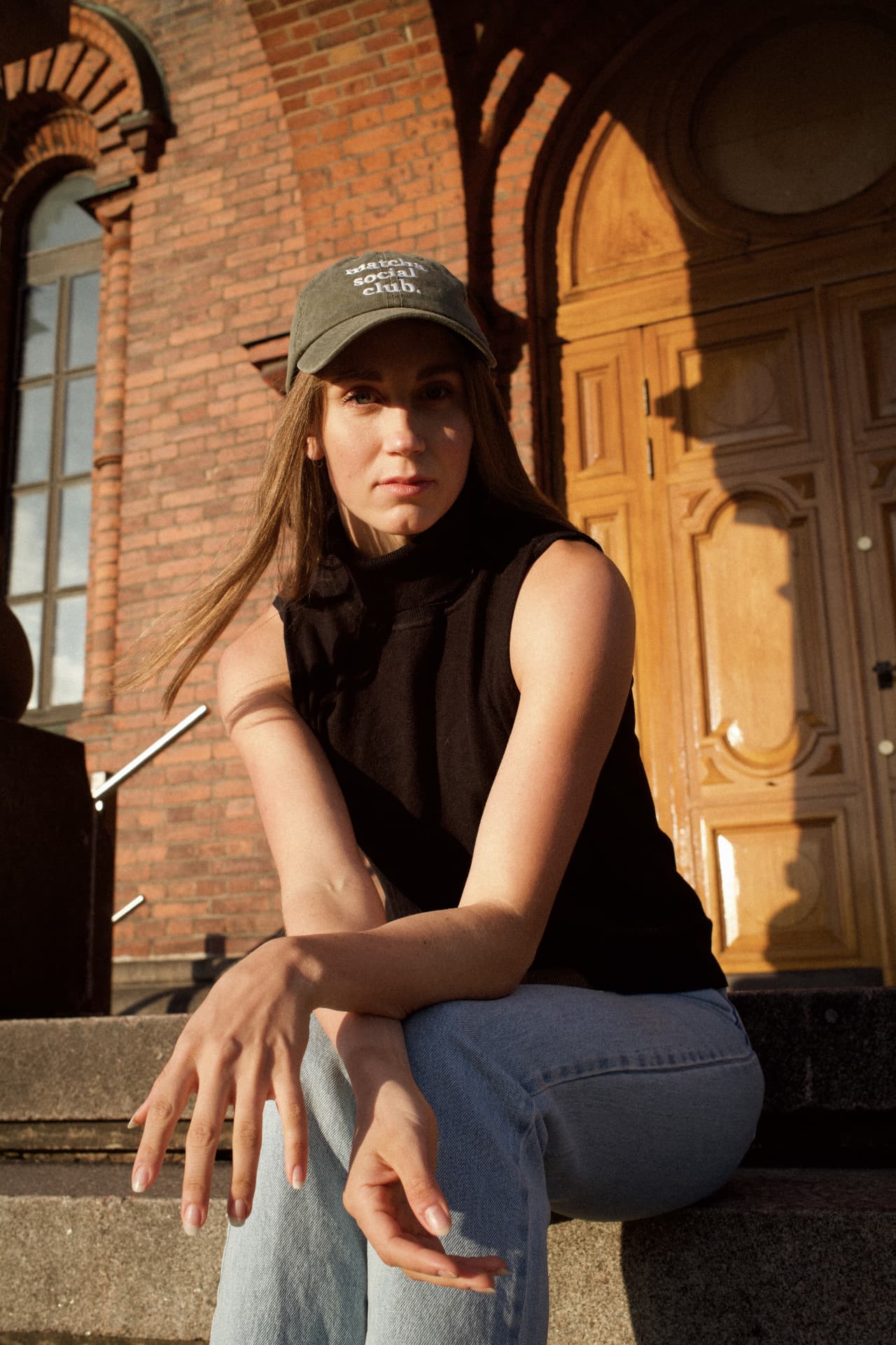 Viivi Lehikoinen sitting on steps wearing a black top and cap