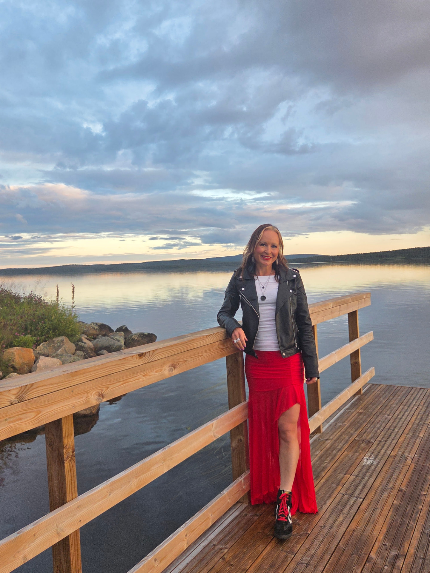 Riitta-Liisa Lassila smiling on a lakeside pier at sunset