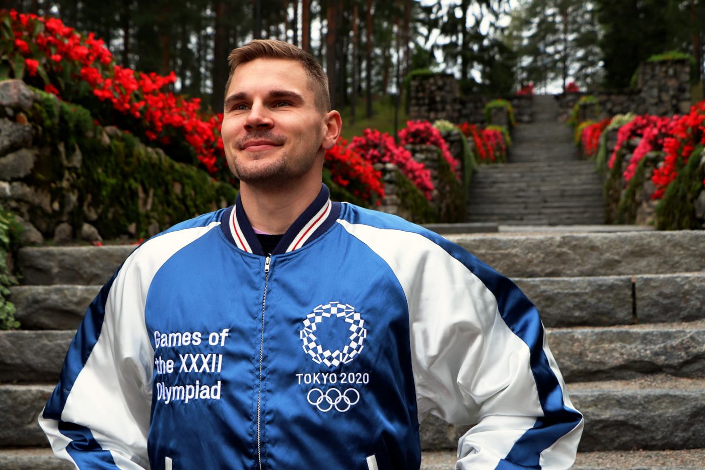 Elmo Lakka wearing a Tokyo 2020 Olympic jacket in front of stone steps.