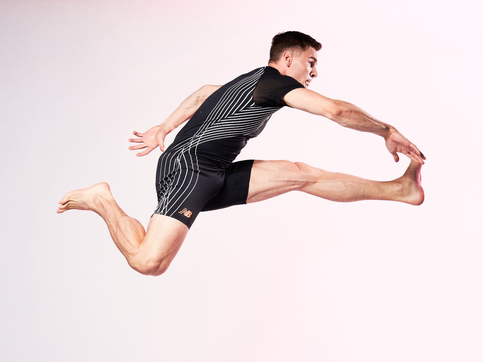 Elmo Lakka in a hurdling pose in a studio photograph against a light background.