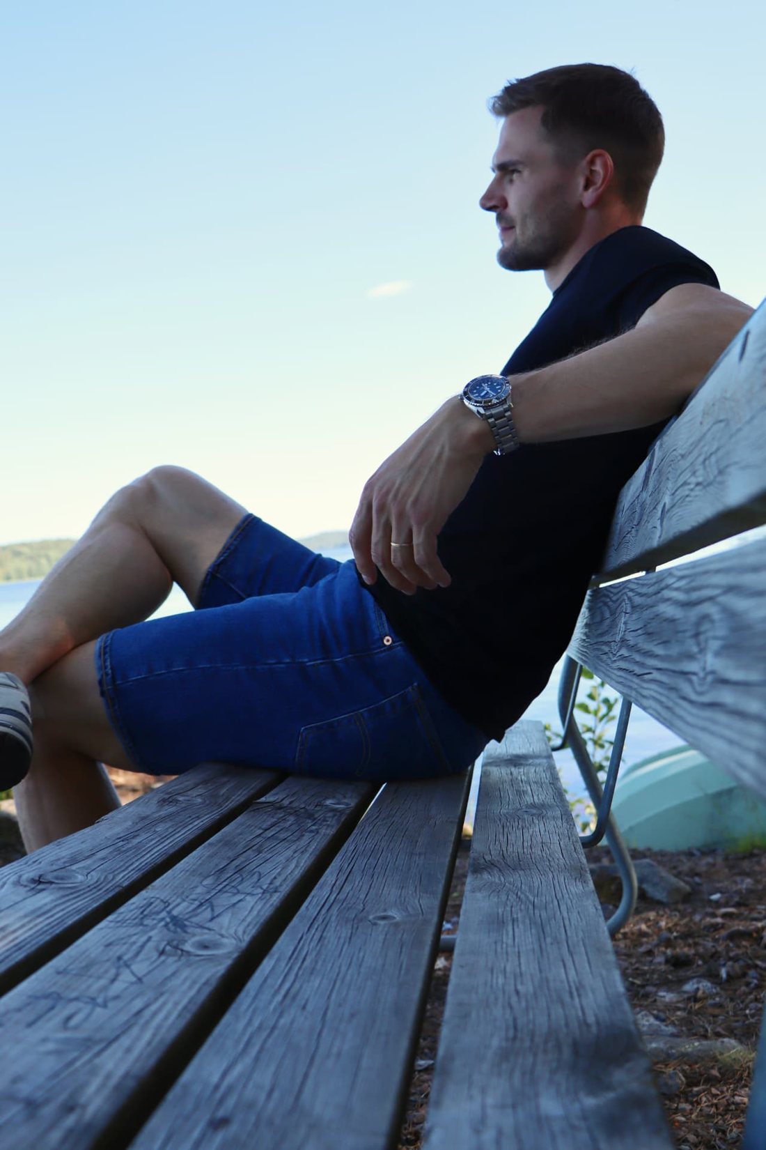 Elmo Lakka sitting on a wooden bench by the water.